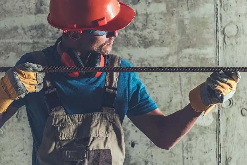 pracownik budowy trzymający w rękach stalowy pręt